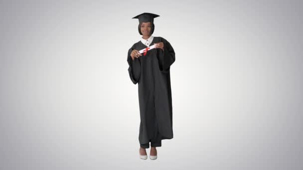 Happy afro graduating female student dancing on gradient background. - Footage, Video