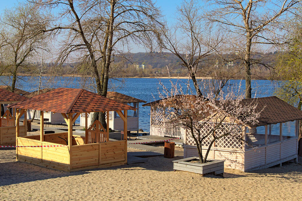 Fechado pequenos pavilhões de praia de madeira de café ao ar livre na praia perto do rio Dnipro, em Kiev. Bela manhã de primavera. Período de isolamento na cidade. Prevenção do vírus da Corona (Covid-19). Ucrânia
. - Foto, Imagem