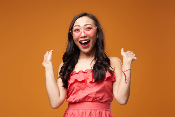 Screaming woman in pink glasses on empty orange background - Фото, изображение