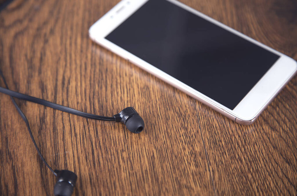 Earphone and smart phone on the table background - Foto, immagini
