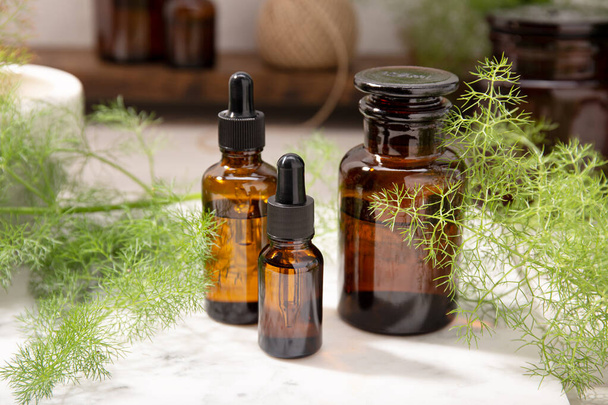 Fennel essential oil on amber bottles. Herbal oil for skin care, aromatherapy and natural medicine - Photo, Image
