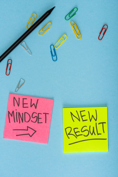 Top view of sticky notes with new mindset and new result lettering with paper clips and pencil on blue - Photo, Image