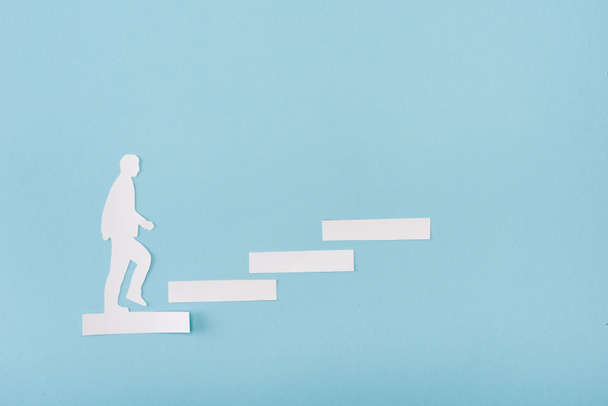 Вид сверху бумажного человека на карьерной лестнице на голубом фоне
  - Фото, изображение