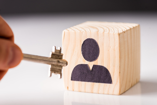 Cropped view of man putting key in cube with painted man on white and black - Photo, Image