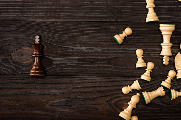 Widok z góry unikalny brązowy król z białymi pionkami szachowymi na drewnianym tle - Zdjęcie, obraz
