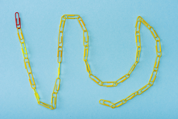 Top view of chain with unique red and yellow paper clips on blue - Photo, Image