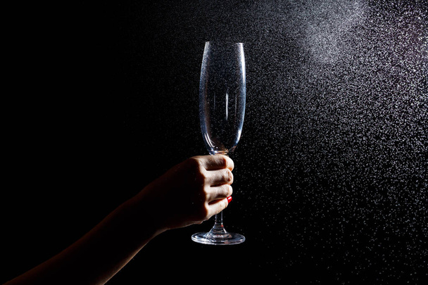 Black background on it is a close-up of a clean glass in his hand. Spray on a glass of water. Insulated glass - Foto, afbeelding