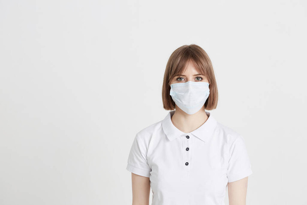 A young girl doctor in a surgical mask is preparing to receive patients with the virus. - Fotografie, Obrázek