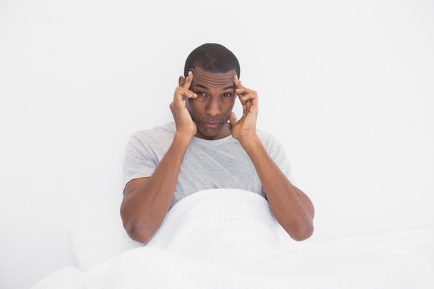 Afro man suffering from headache in bed - 写真・画像