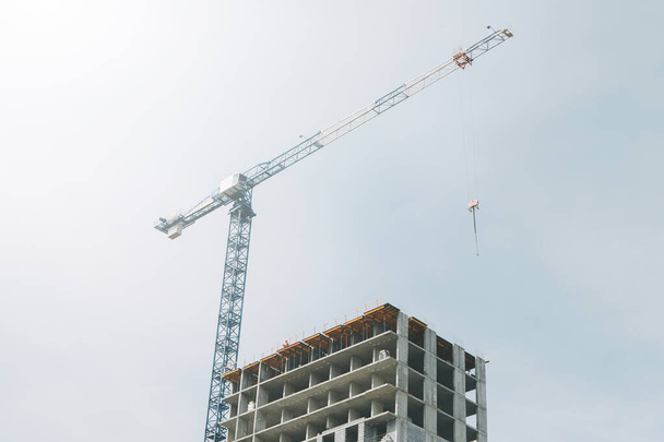  Cranes in the construction of high-rise buildings. Construction of floor coverings. Construction of a building made of solid concrete. - Photo, Image