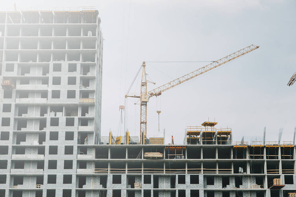  Cranes in the construction of high-rise buildings. Construction of floor coverings. Construction of a building made of solid concrete. - Foto, Bild