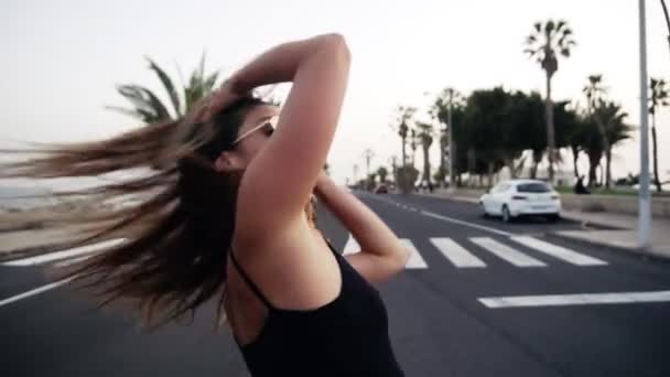 Zamknij nagranie seksownej dziewczyny machającej włosami przed kamerą, poruszającej ciałem zmysłowo w tańcu. Dziewczyna w okularach przeciwsłonecznych tańczy na drodze hip hop na terenie ośrodka. Zwolniony ruch - Materiał filmowy, wideo