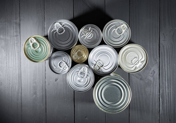 Group of tin cans on dark gray black boards. Topview or above view - 写真・画像