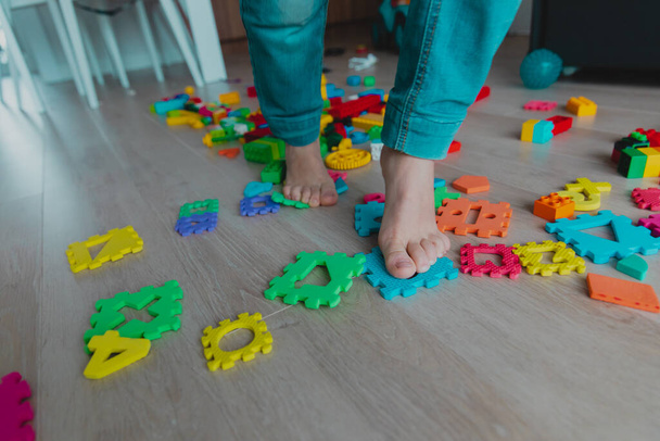 demasiados juguetes en casa- niño pisa los juguetes tratando de pasar por - Foto, Imagen