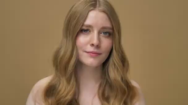 Une jeune femme souriante à moitié nue aux cheveux longs montre un geste pouce vers le haut isolé sur fond beige
 - Séquence, vidéo