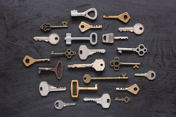 various metal keys on a black wooden background, top view. flat lay. - Fotó, kép