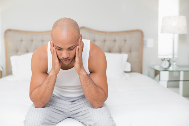 Bald man suffering from headache in bed - Foto, afbeelding