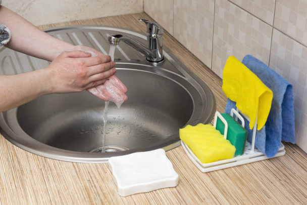 Mujer lava bien las manos con jabón y grifo de agua en la cocina
 - Foto, Imagen