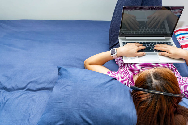 Ein Mädchen, das von zu Hause aus an ihrem Bett mit Laptop und Headset arbeitet. Mama, die während ihres Aufenthalts zu Hause arbeitet, kündigt wegen Virusausbruch - Foto, Bild