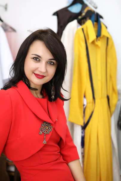 Beautiful girl in a red dress on the dresses. The designer shows his dresses. Beautiful girl in a red dress in a tailoring studio. Exclusive tailoring of dresses to order. - Foto, Bild