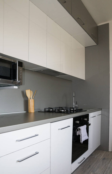 Skandinavisch, Minimalismus nach Hause. White Kitchen Design. Moderne weiß glänzende Küche mit silbernem Akzent und Accessoires. Gemütliche, schöne, funktionale Küche. - Foto, Bild