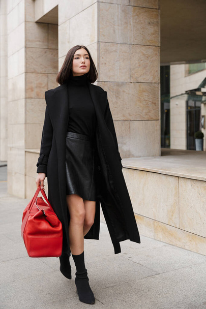 Attractive young brunette woman wearing autumn coat walking in a street - 写真・画像
