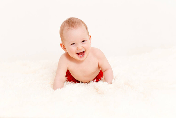 Caucasian smiling little girl crawl on bed over white background . an infant under one year old. eight months. only in panties - Φωτογραφία, εικόνα