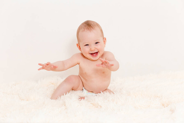 Caucasian cute baby sitting on a white fluffy blanket at home - Фото, зображення