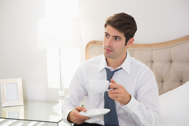 Smiling well dressed man drinking coffee in bed - Photo, image