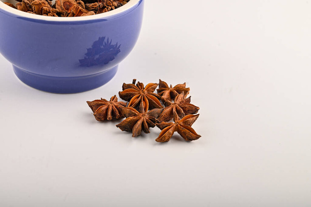 star anise in a blue ceramic spice mortar on a white background. Close up - Photo, Image