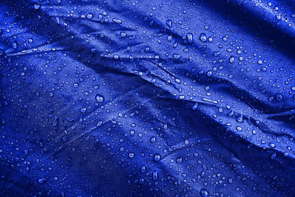 L'eau tombe sur le tissu. L'eau tombe sur fond bleu. Condensé. gouttes d'eau fond
.  - Photo, image