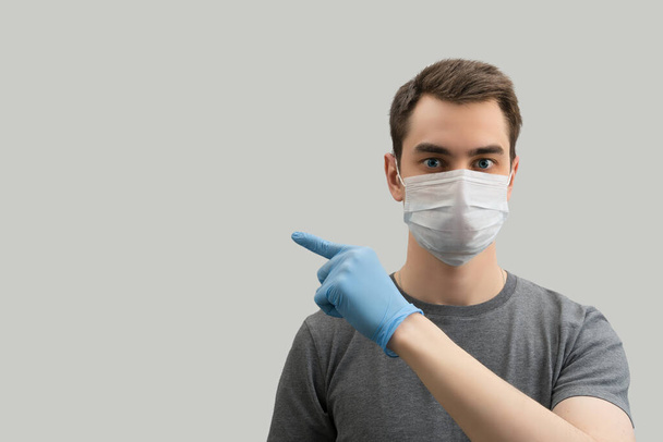 Young european man wearing mask showing tips against the corona virus covid 19  man wearing surgical mask to prevent from virus white\grey background Corona virus pandemic - Fotó, kép