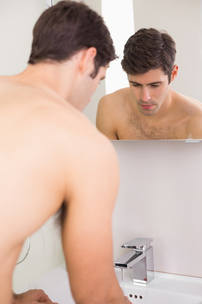 Rear view of tensed shirtless man at washbasin - Photo, image