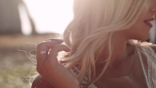 blondes Mädchen glättet ihre Haare bei Sonnenuntergang. Nahaufnahme. - Filmmaterial, Video