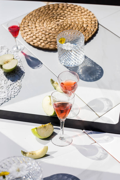  weißer Esstisch mit aufgeschnittenem Apfel und spiegelnden Gläsern - Foto, Bild