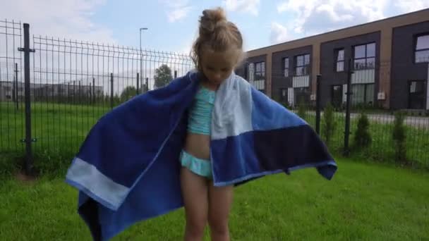 little girl wrapping herself up in a towel after swimming in pool - Footage, Video