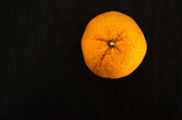One bright juicy orange on a black background,Orange on black background - Фото, изображение