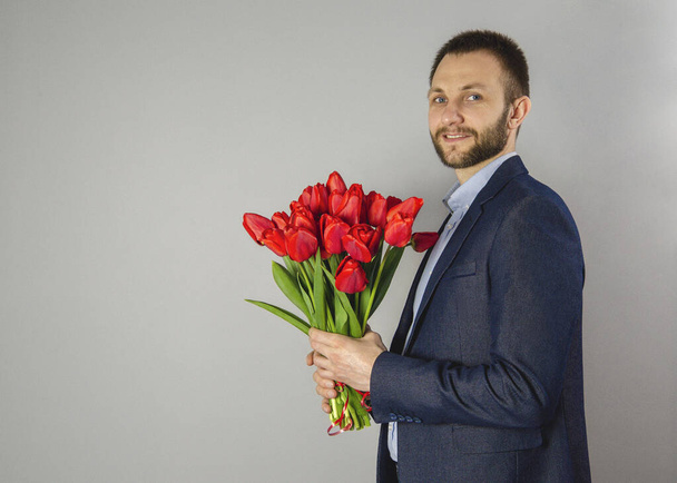 un hombre sostiene tulipanes rojos
 - Foto, imagen