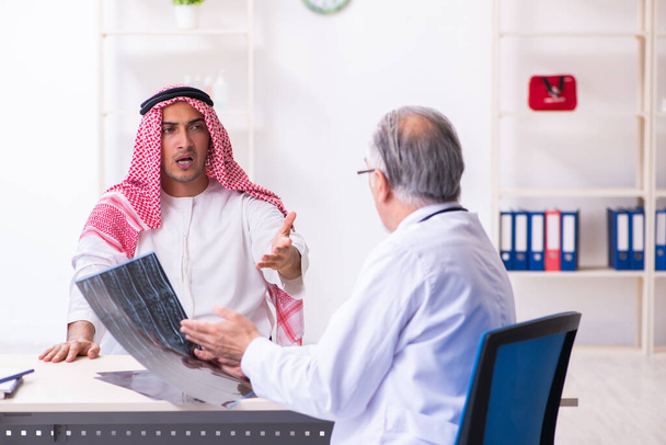 Jovem árabe masculino visitando médico masculino experiente
 - Foto, Imagem