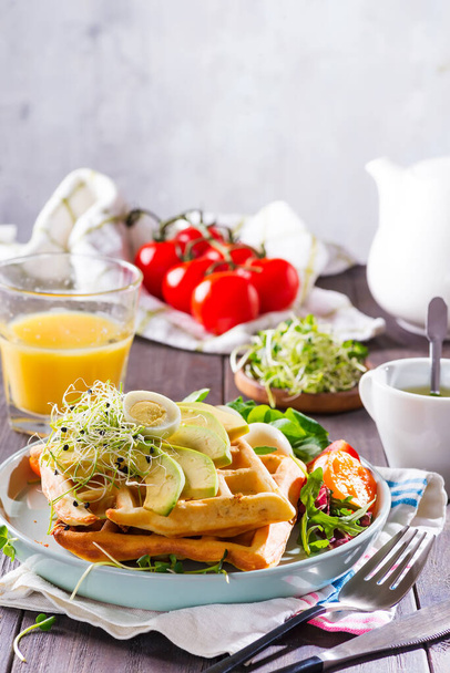 Ontbijt tijd. Wafel met salade, ei, sap en avocado 's als ontbijt. - Foto, afbeelding