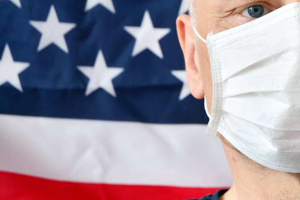 A man in a medical mask on the background of the US flag - Photo, Image