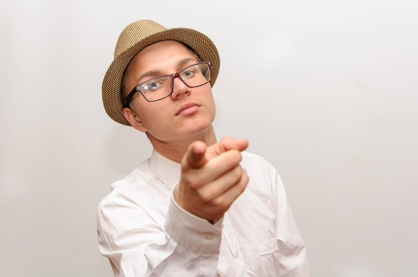 Νεαρός με γυαλιά και καπέλο δείχνει με το δάχτυλο την κάμερα.. - Φωτογραφία, εικόνα