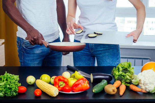 Korean woman wearimg white cotton t-shirt with her african american boyfriend cooking in fry pan bresksast - Foto, Imagem