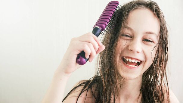 Happy teen girl combs wet hair with smile - Foto, afbeelding