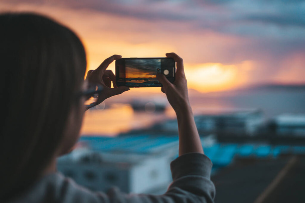 Γυναίκα τραβώντας φωτογραφίες της θάλασσας από το μπαλκόνι με ένα smartphone - Φωτογραφία, εικόνα