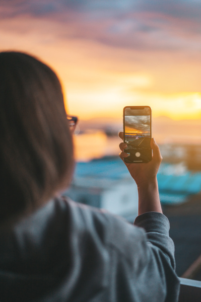Женщина фотографирует море с балкона со смартфоном
 - Фото, изображение