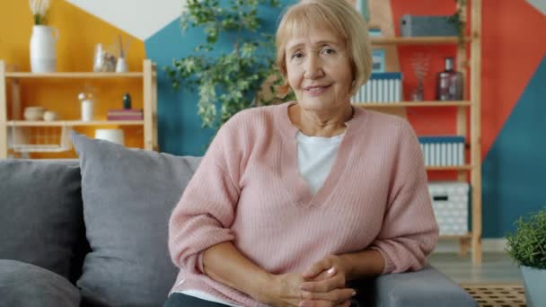 Slow motion portrait of elegant elderly blonde smiling looking at camera in apartment - Πλάνα, βίντεο
