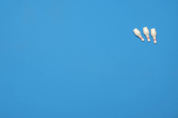 Three knocked over bowling pins after picking up a spare on a blue background with copy space and room for text with a right side composition - 写真・画像