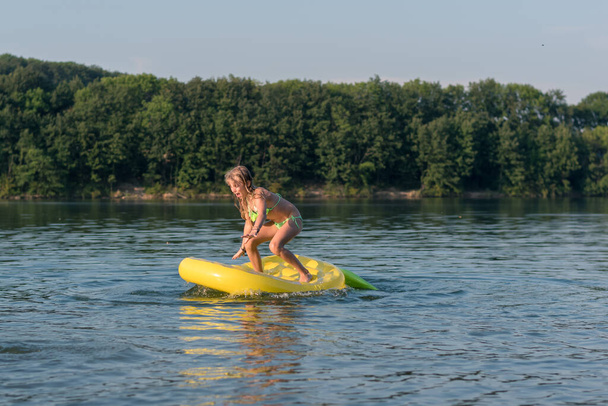 půvabná dívka vyvažování ve žluté nafukovací airbed v řece povrchu  - Fotografie, Obrázek