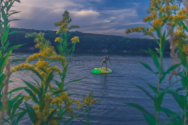 festői kilátás sárga virágok és a lány szórakozás vidéki tó színes naplemente - Fotó, kép